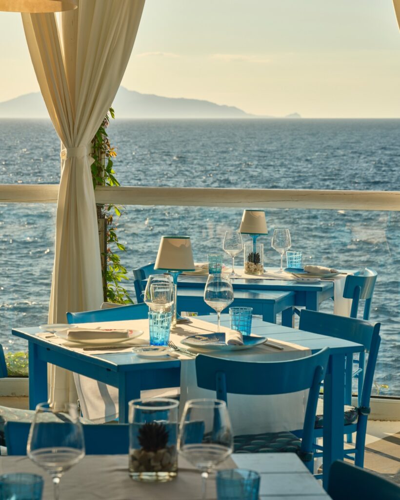 Mesas azuis com vista panorâmica para o mar no Il Riccio em Capri, um dos restaurantes mais belos da Itália.