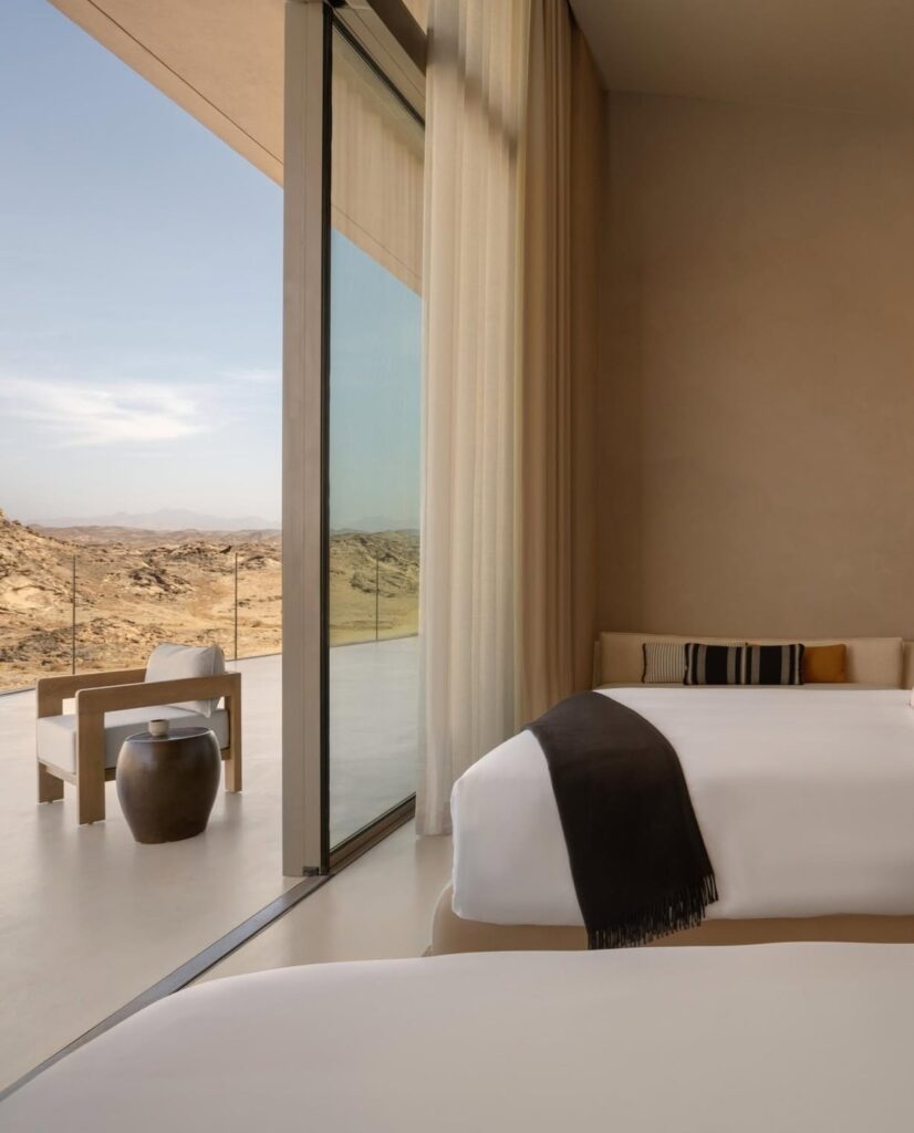 Quarto minimalista com esquadria ampla voltada para o deserto no Desert Rock Hotel.