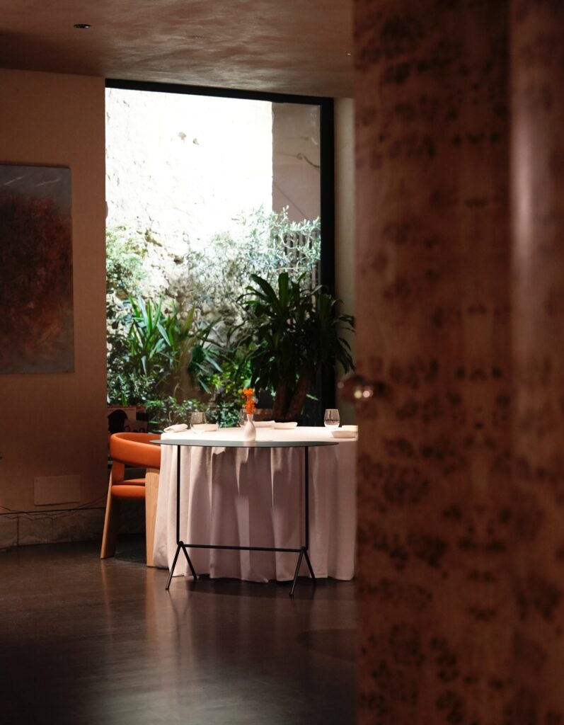 Mesa posta no restaurante La Madia em Licata integrada ao jardim de inverno mediterrâneo, destaque dos restaurantes mais belos da Itália.