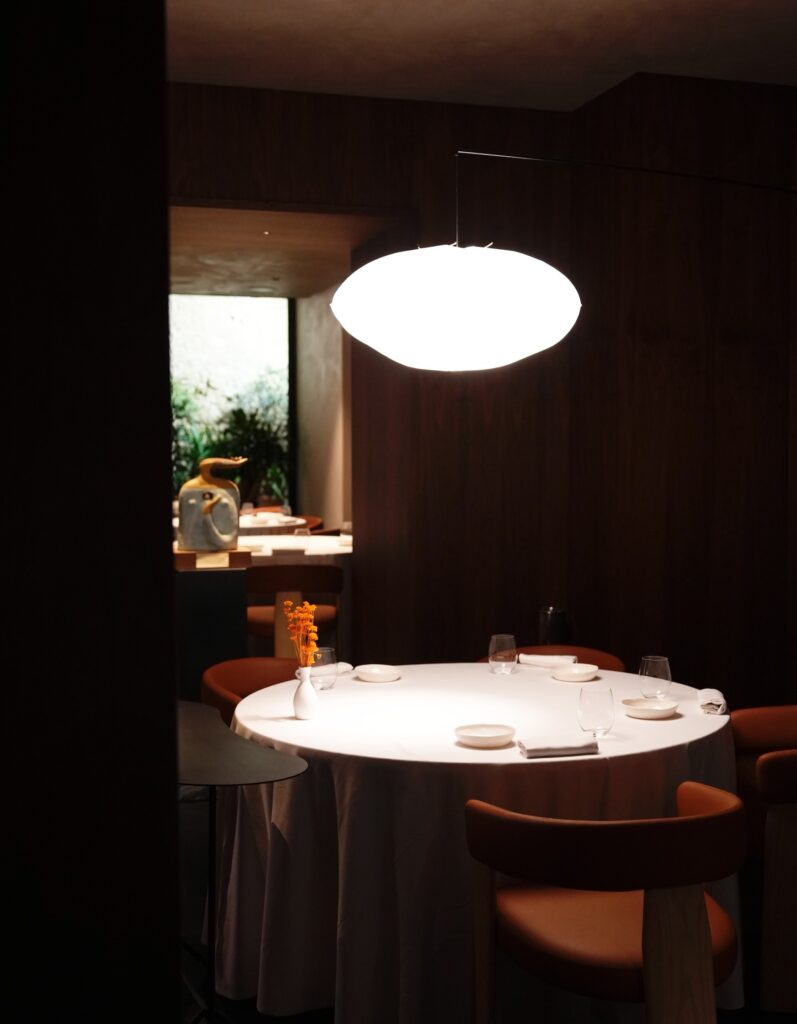 Luminária pendente escultural sobre a mesa de jantar no La Madia em Licata, referência de design nos restaurantes mais belos da Itália.