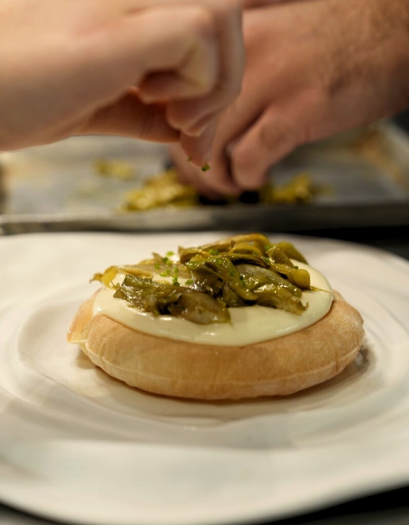 Finalização artesanal de prato da alta gastronomia no La Madia em Licata, marco culinário dos restaurantes mais belos da Itália.