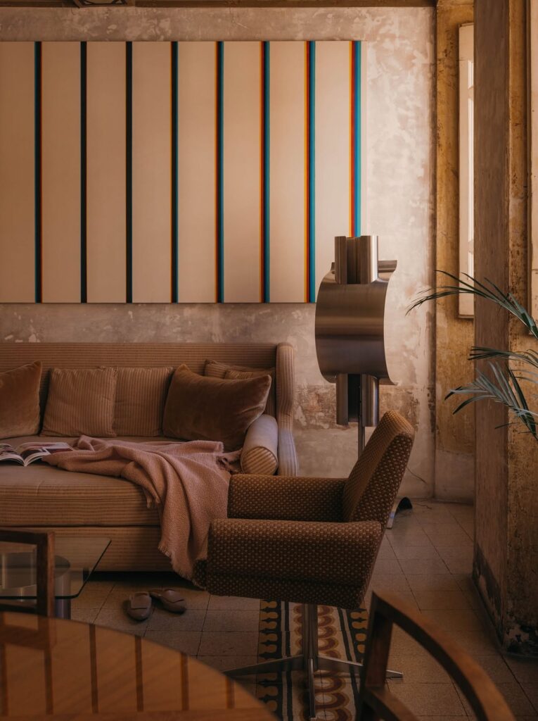 Salão de estar com mobiliário vintage italiano e luminária metálica no hotel G-Rough Roma.