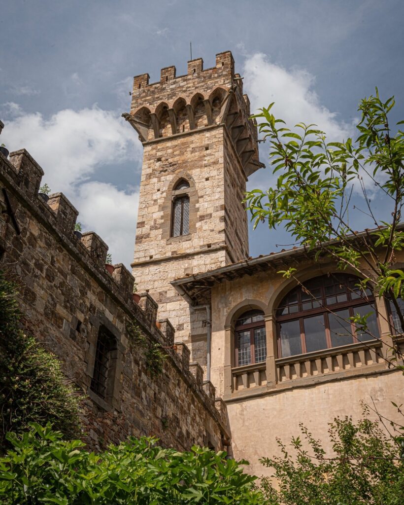 Fachada e torre medieval em pedra da Badia onde fica a Osteria di Passignano no Chianti, destacando a arquitetura histórica toscana.
