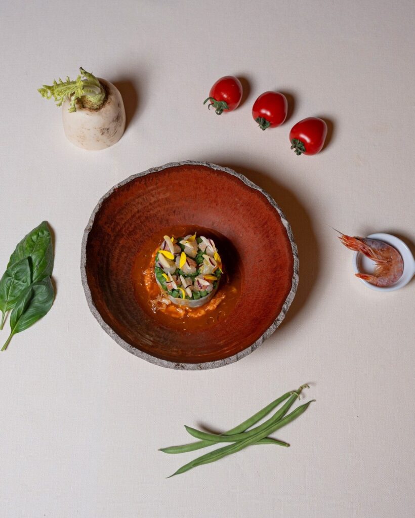 Vista aérea de prato autoral e ingredientes toscanos frescos sobre linho na Osteria di Passignano, valorizando o design gastronômico.