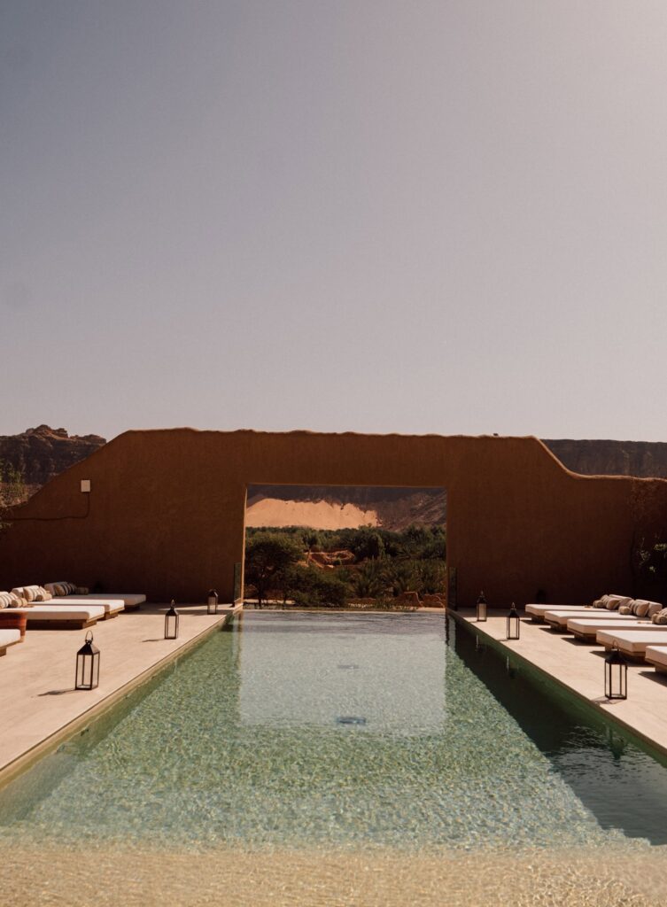 Piscina com pórtico de adobe emoldurando a paisagem montanhosa no Dar Tantora.