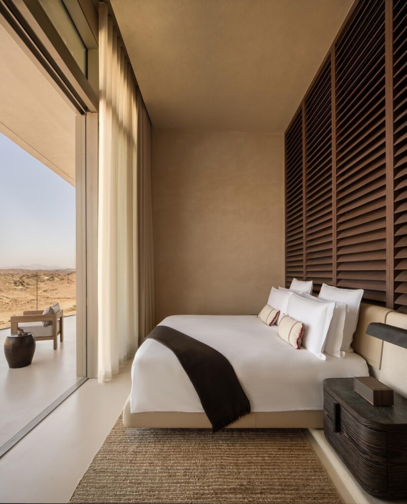 Quarto de casal com cabeceira ripada de madeira e terraço no Desert Rock Hotel.