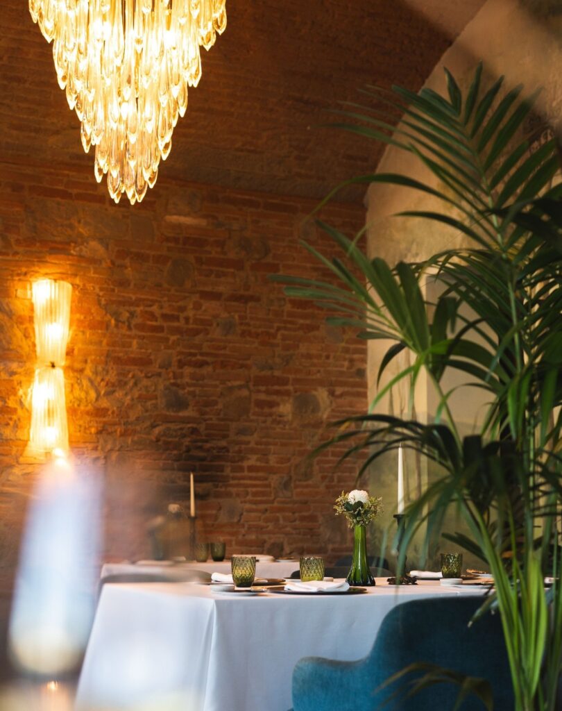 Mesa intimista do Saporium, um dos restaurantes mais bonitos na Itália, com parede de tijolos e lustre de cristal.