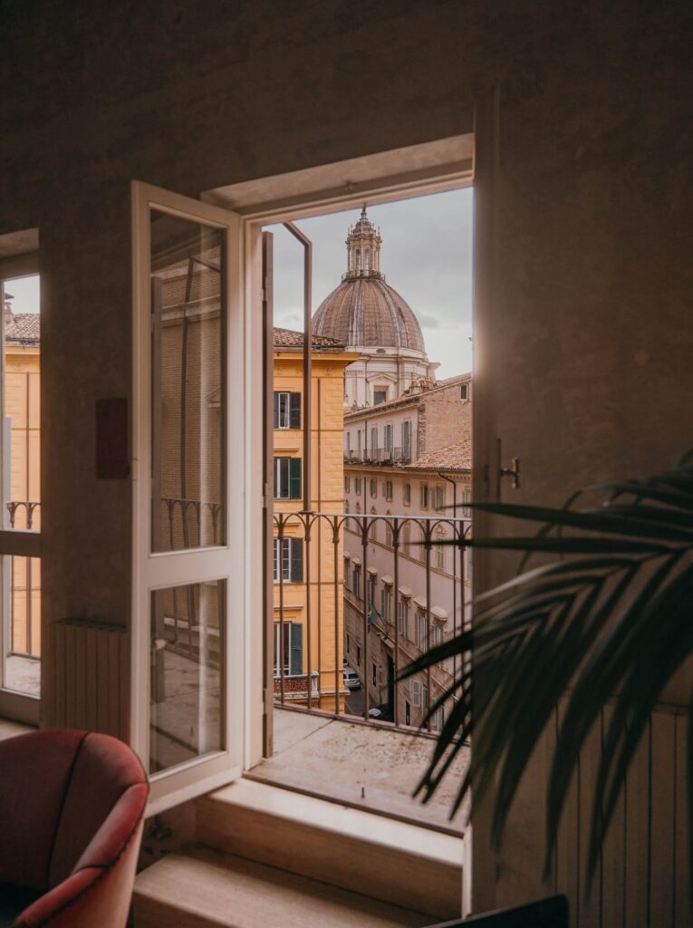 Vista da janela do hotel boutique G-Rough Roma para cúpula barroca e arquitetura histórica da cidade.