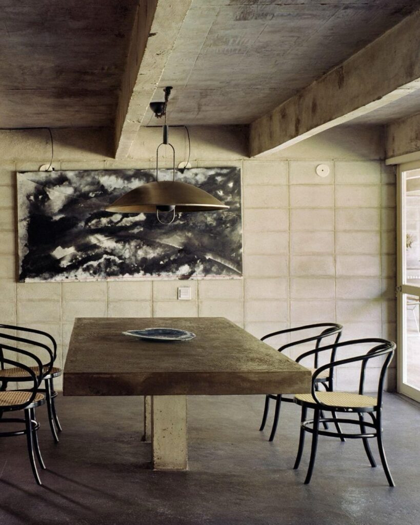 Mesa de concreto e pintura abstrata na sala da Casa Ateliê Tomie Ohtake, museu pequeno em são paulo repleto de design e arte brasileira.