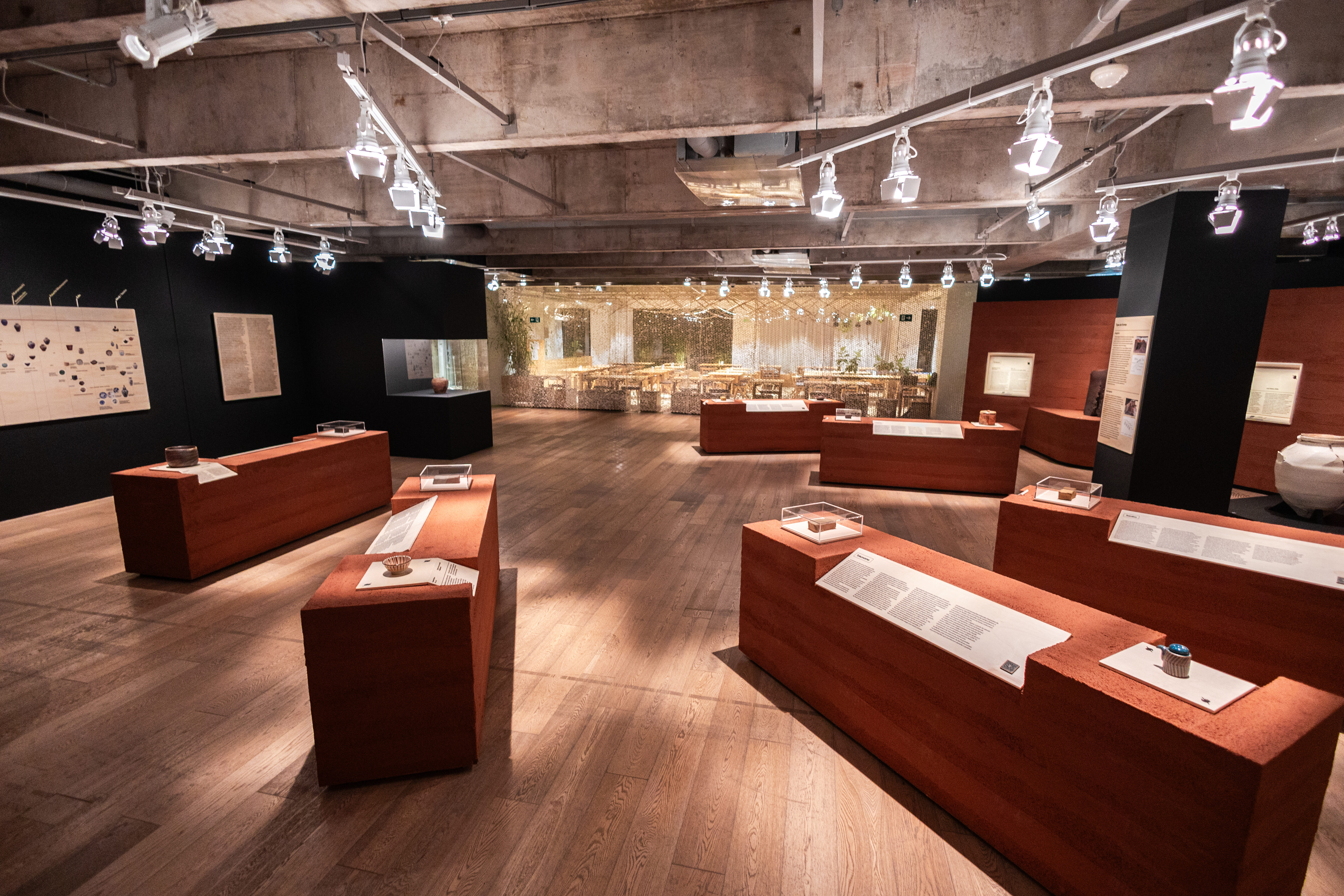 Vista panorâmica da expografia com plintos terrosos na exposição Cerâmicas no Japan House São Paulo.
