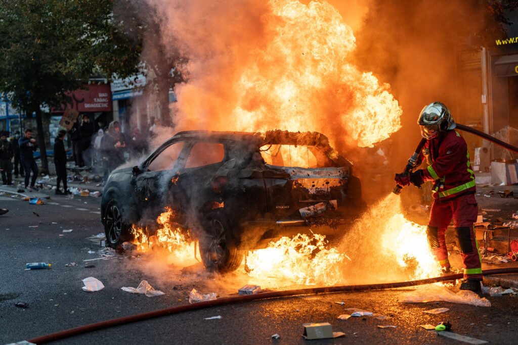 Bombeiro apagando inc&ecirc;ndio em autom&oacute;vel durante protestos na Europa (Paris, 2026)
