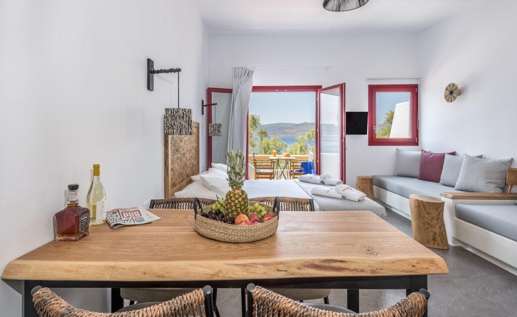 Studio contemporâneo em Syrmatas no Magic Klima III com mesa de borda orgânica, cabeceira em mosaico e esquadrias bordô.