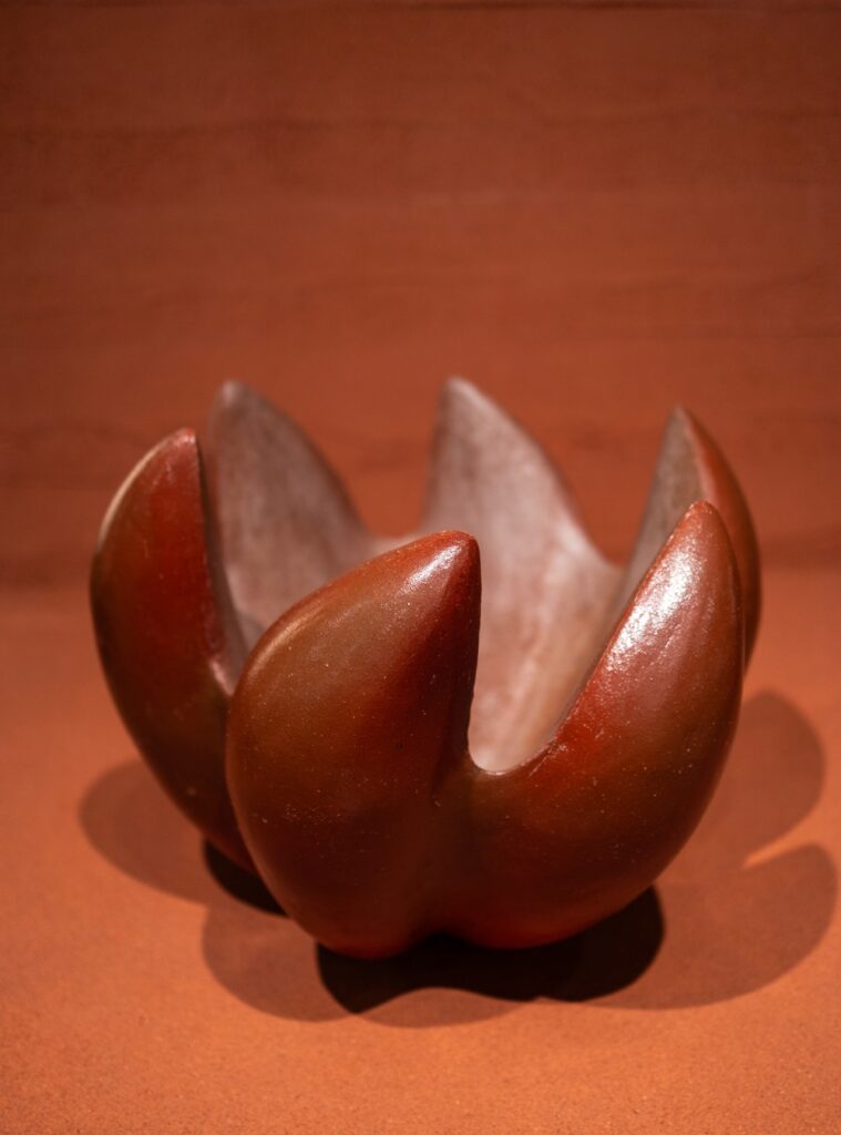 Vaso escultórico em cerâmica avermelhada orgânica com pétalas curvas, em destaque em exposições em São Paulo na Japan House.