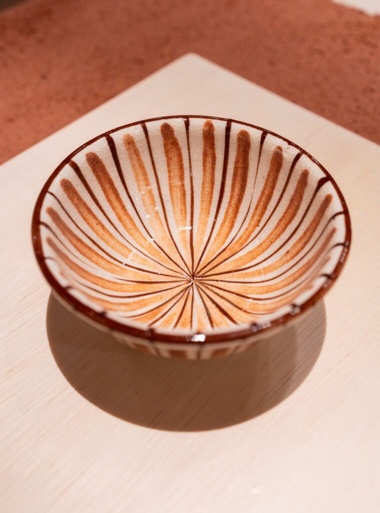 Tigela cerâmica com padrão floral radial e craquelado em destaque nas exposições em são paulo da Japan House.