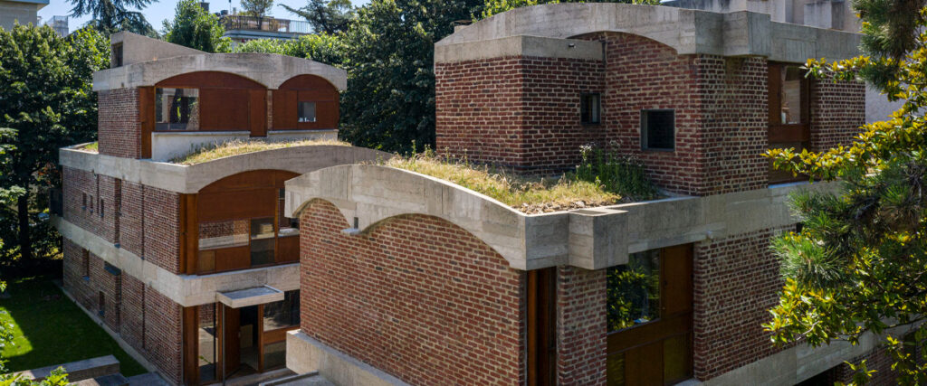 Fachada das Maisons Jaoul com tijolos aparentes, abóbadas de concreto e teto-jardim, marco do movimento brutalista de Le Corbusier.