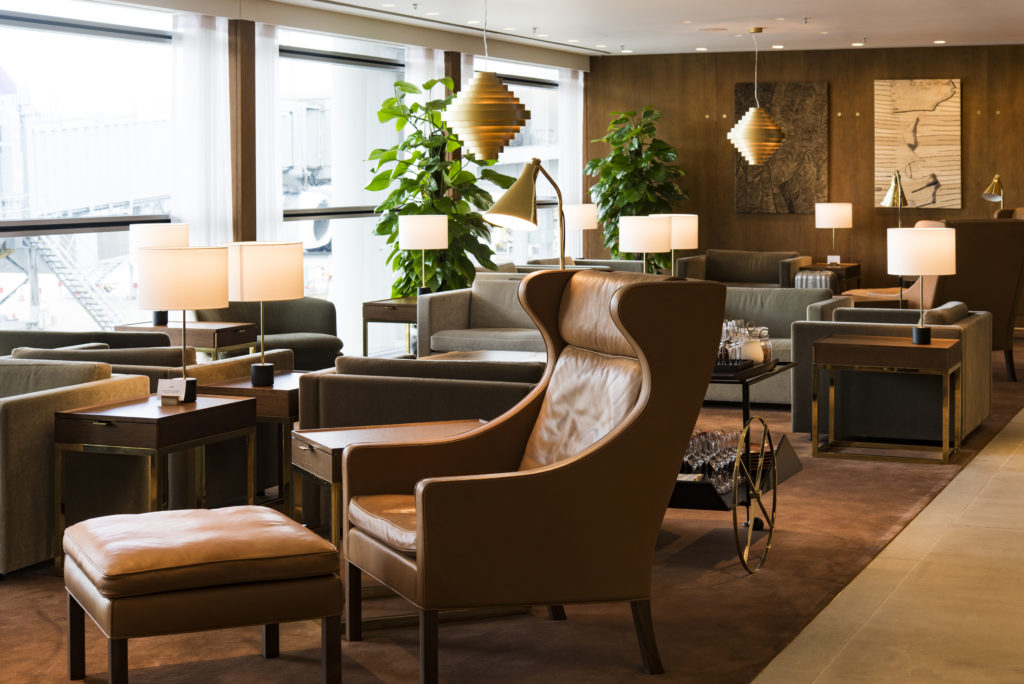 Lounge The Pier da Cathay Pacific por Ilse Crawford com poltrona bergère de couro e marcenaria em nogueira.