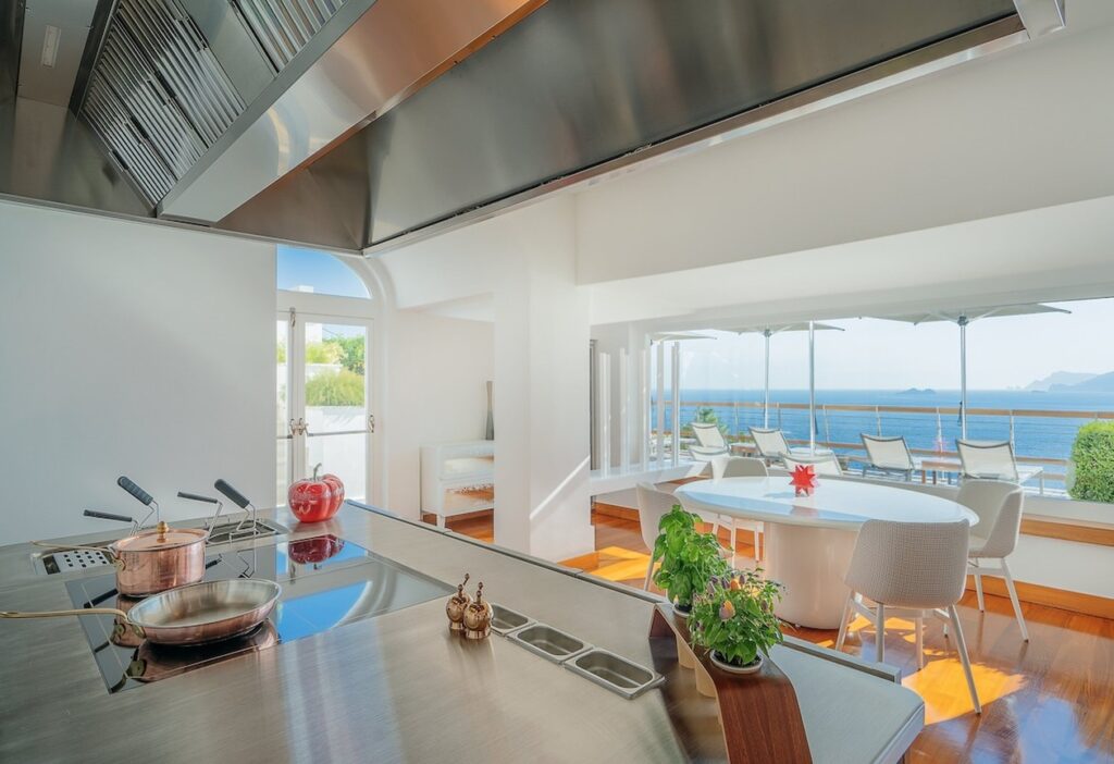 Cozinha contemporânea de design com ilha em inox e mesa de jantar integrada no hotel Casa Angelina.
