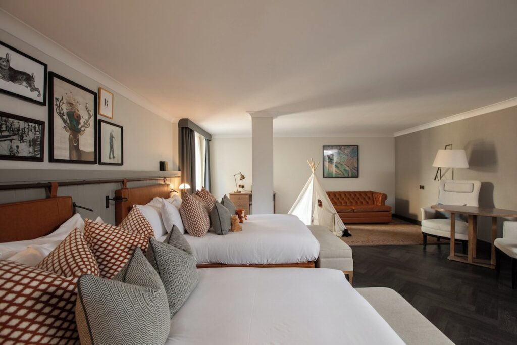 Suíte familiar ampla com camas queen e sofá de couro capitonê no Kimpton Charlotte Square.