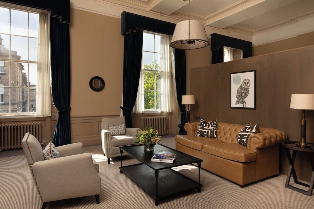 Sala de estar da suíte clássica com sofá de couro conhaque no Kimpton Charlotte Square.
