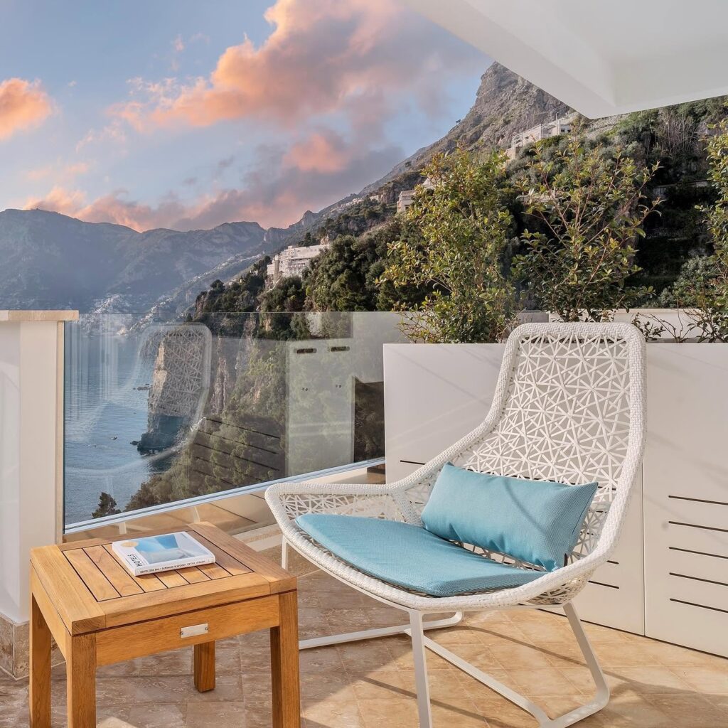 Varanda com poltrona de design contemporâneo e vista panorâmica para as falésias no hotel Casa Angelina.