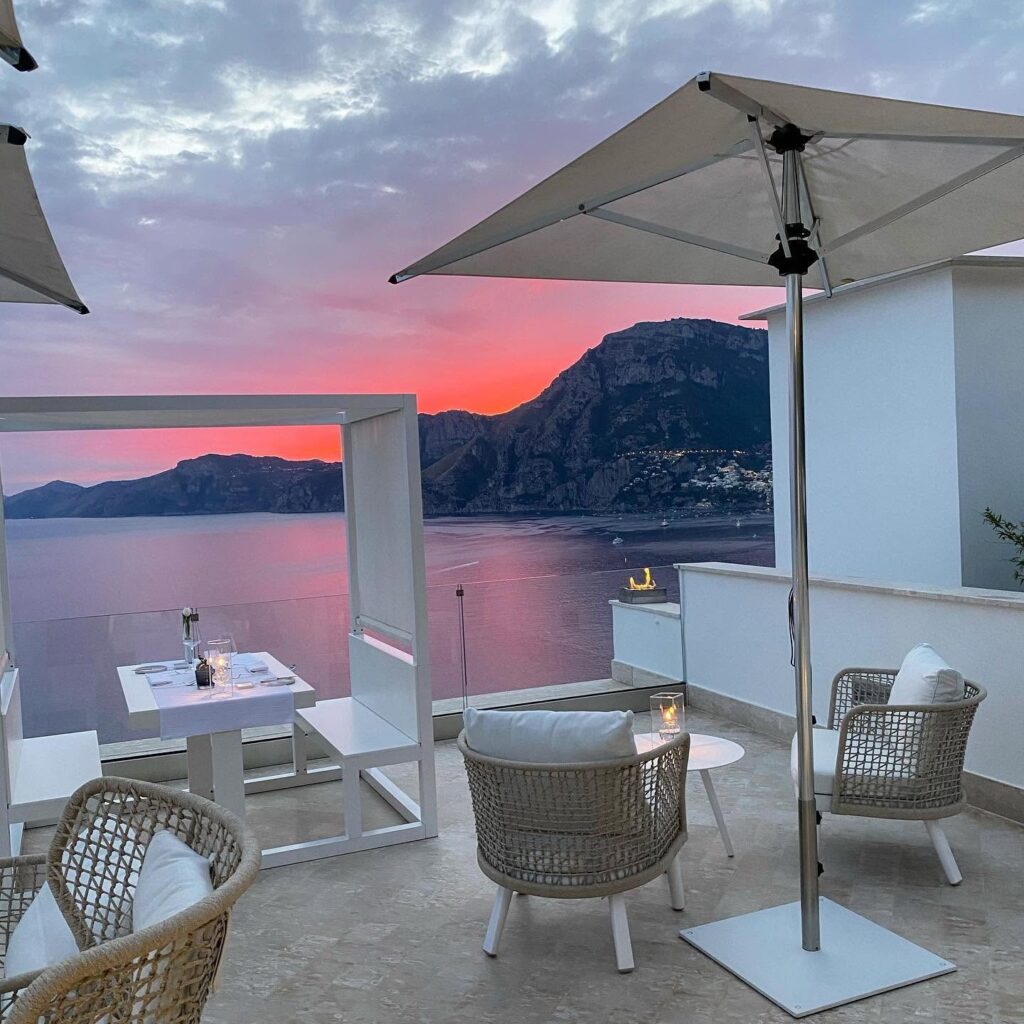 Lounge no terraço com poltronas confortáveis e céu em tons de magenta no hotel Casa Angelina.