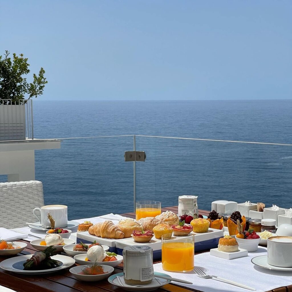 Café da manhã servido ao ar livre no terraço panorâmico com vista infinita para o mar no hotel Casa Angelina.