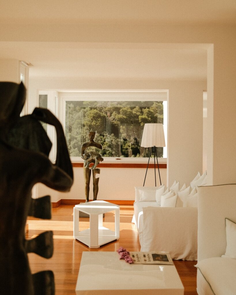 Sala de estar com esculturas de arte contemporânea e mobiliário branco no hotel Casa Angelina.