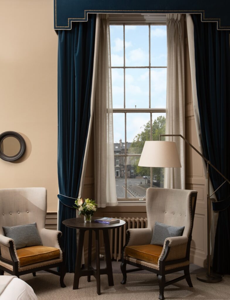 Área de estar da suíte com cortinas de veludo e janelas georgianas no Kimpton Charlotte Square.