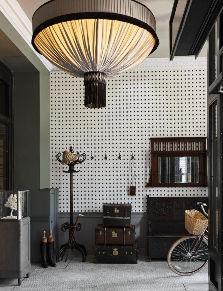 Foyer de entrada com papel de parede gráfico e pendente escultural no Kimpton Charlotte Square.